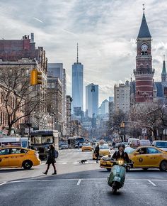 a city street filled with lots of traffic and people crossing the street in front of tall buildings