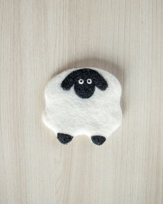 a sheep brooch sitting on top of a wooden table