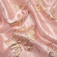 an image of a pink and gold fabric with flowers on it's side, close up