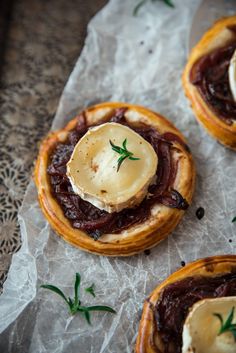 three pastries on wax paper with green garnish and some type of sauce