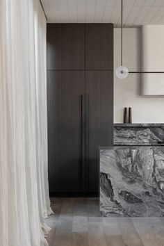 a kitchen with marble counter tops and wooden cabinets, along with white drapes covering the walls