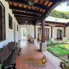 an outdoor patio with benches and potted plants on the side, surrounded by greenery