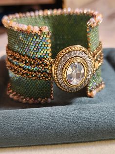 a close up of a bracelet on top of a cloth covered table with other items