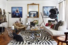 a living room filled with lots of furniture and art on the wall above it's fireplace