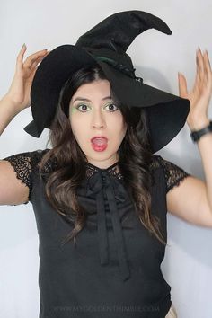 a woman wearing a witches hat with her hands in the air while making a funny face