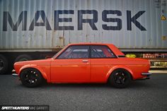 an orange car is parked in front of a truck