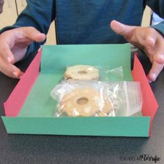 a person sitting at a table with a doughnut in a box