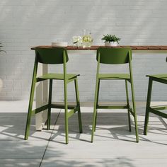 two green chairs sitting at a table with white flowers on it and a potted plant in the background