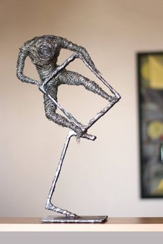 a metal sculpture sitting on top of a wooden table next to a framed art piece