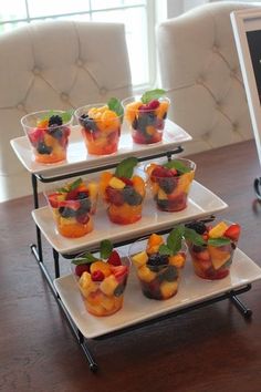 four tiered trays filled with fruit on top of a wooden table