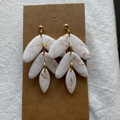 three pairs of white and gold earrings sitting on top of a piece of paper