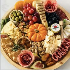 a wooden platter filled with different types of cheeses and meats on top of each other