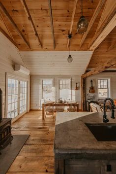 a kitchen and living room with wood flooring in an old log cabin style home