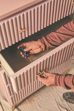 a person holding a cell phone in front of a radiator that is being worked on