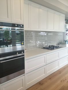 a kitchen with white cabinets and black stove top ovens in front of a window