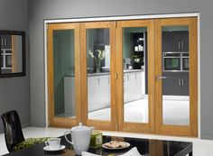 a kitchen with wooden doors and white counter tops next to a dining room table in front of a mirror