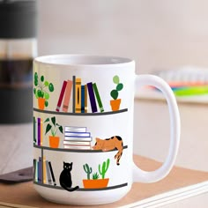 a white coffee mug with books and cats on it