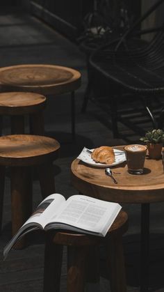 an open book sitting on top of a wooden table next to some chairs and tables