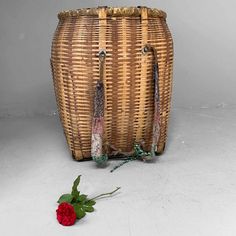 a basket with flowers on the floor next to it and a red rose laying in front of it