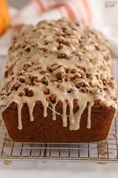 a close up of a loaf of bread with icing on a wire cooling rack