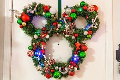 a mickey mouse wreath hanging on the front door with christmas ornaments around it and candy canes