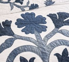 a blue and white quilt with flowers on the bottom, along with an intricately designed design