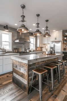 a kitchen with an island and stools in the center, surrounded by wooden flooring