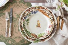 a place setting with plates, silverware and napkins on a patterned table cloth