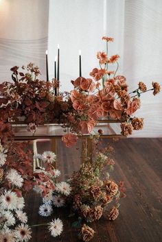 an arrangement of flowers and candles on a table