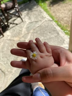 a person holding a tiny white flower in their left hand with the other hand extended out