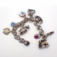 "Vintage ornate 830 silver chain bracelet decorated with 8 figural dangle charms, representing different European destinations. Some charms are accented with colorful enamel, one charm is silver-plated. This lovely bracelet is 7 1/2\" long, weighing 46.8 grams or 1.5 ozs Troy. EA3729" Collectible Metal Charm Bracelet With Lobster Clasp, Antique Metal Bracelet With Charms, Silver Enamel Jewelry With Charms, Metal Charms With Lobster Clasp For Collectors, Collectible Vintage Charm Metal Bracelet, Vintage Enamel Charms Jewelry, Silver Metal Chain Bracelet With Dangling Charms, Enamel Charms Bracelet, Metal Dangling Charms For Collectibles