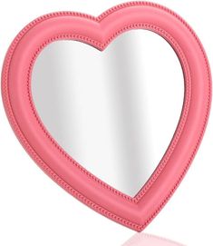 a pink heart shaped mirror sitting on top of a table