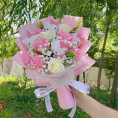 a person holding a pink and white bouquet in their hand with hello kitty on it