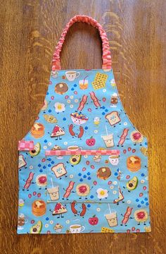 a blue apron with donuts and other foods on it sitting on a wooden table