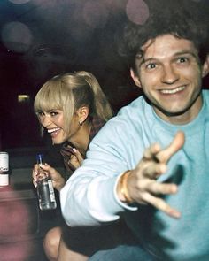 a man and woman sitting next to each other in front of a table with drinks