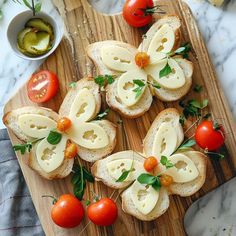 several pieces of bread with cheese and tomatoes on them sitting on a wooden cutting board