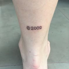 a woman's foot with the number 2000 tattooed on her left side calf area