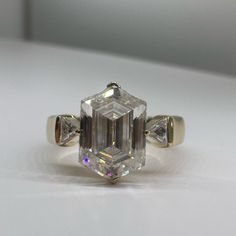 an emerald cut diamond ring on a white surface