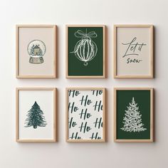 four framed christmas cards on a white wall with green and white ornaments hanging from them