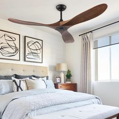 a bedroom with a bed, ceiling fan and two pictures on the wall above it