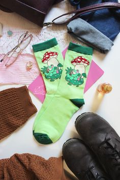 Dive into your next book wearing these comfortable, knitted cotton Ribbeting Read Socks. Adorned with a cute frog nestled under a mushroom to read his favourite book, your style will be as unique as the stories that accompany you! ♡ Medium fits American size W 8-11, M 7-9.5 ♡ Large fits American size W 9.5-13, M 8-11 --------------- ♡ 1 pair of 2 socks ♡ Machine washable ♡ Jaquard (woven, not printed, so the pattern won't fade!) ♡ Crew style ♡ 80% cotton, 17% nylon, 3% spandex Cute Frog, Cute Frogs, Patterned Socks, Knit Cotton, Crew Socks, Favorite Books, To Read, Stuffed Mushrooms, Socks