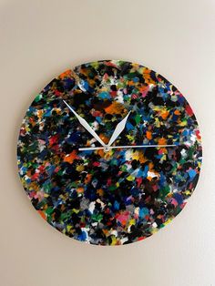 a clock made out of multicolored paint splattered on the face of it