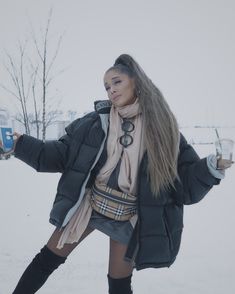 a woman standing in the snow with her arms out