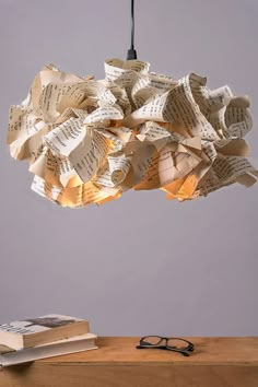 a light made out of books hanging from a ceiling fixture with reading glasses on it