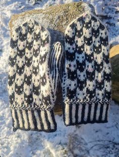 two mittens sitting on top of a rock in the snow