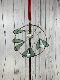 a wind chime hanging from a red ribbon on top of a wooden table next to a white wall