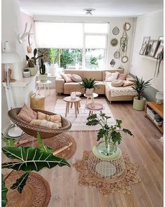 a living room filled with lots of furniture and plants on top of hard wood flooring