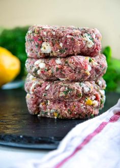 three hamburger patties stacked on top of each other next to broccoli and lemons