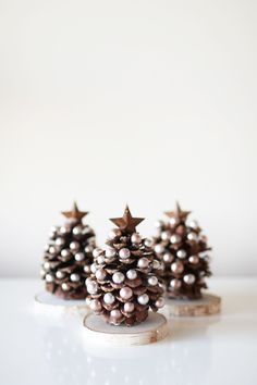 three small pinecone trees sitting on top of a white table next to each other