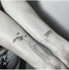 two people with tattoos on their arms and one has a paper airplane in the sky